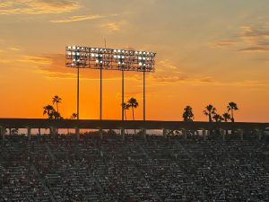 Los Angeles skyline at night with a brightly lit sports arena symbolising the LA28 Olympic Games and mega-event economy.